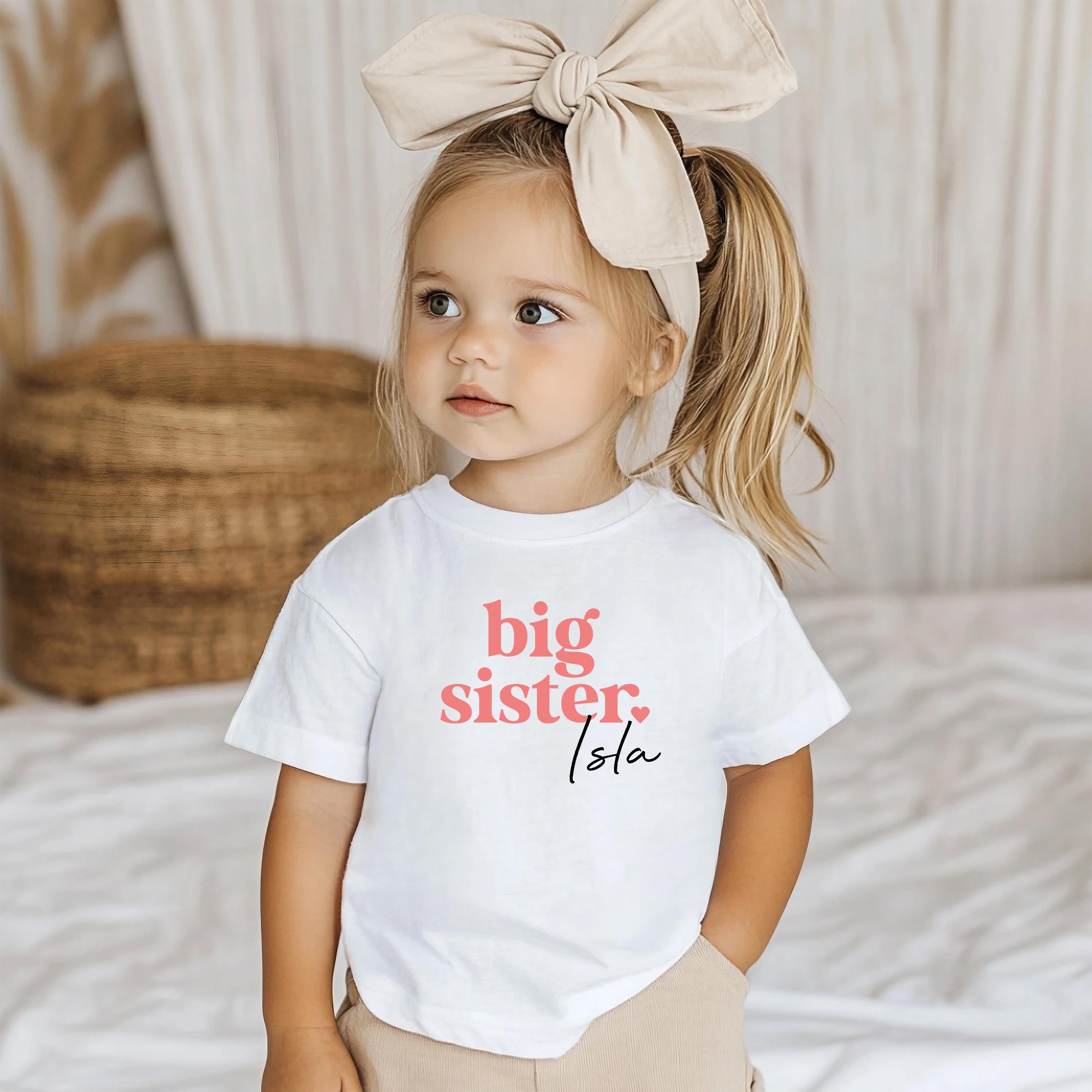 Close-up of 'Big Sister' text on white cotton kids' t-shirt – perfect for baby announcement, sibling reveal, or big sister gift