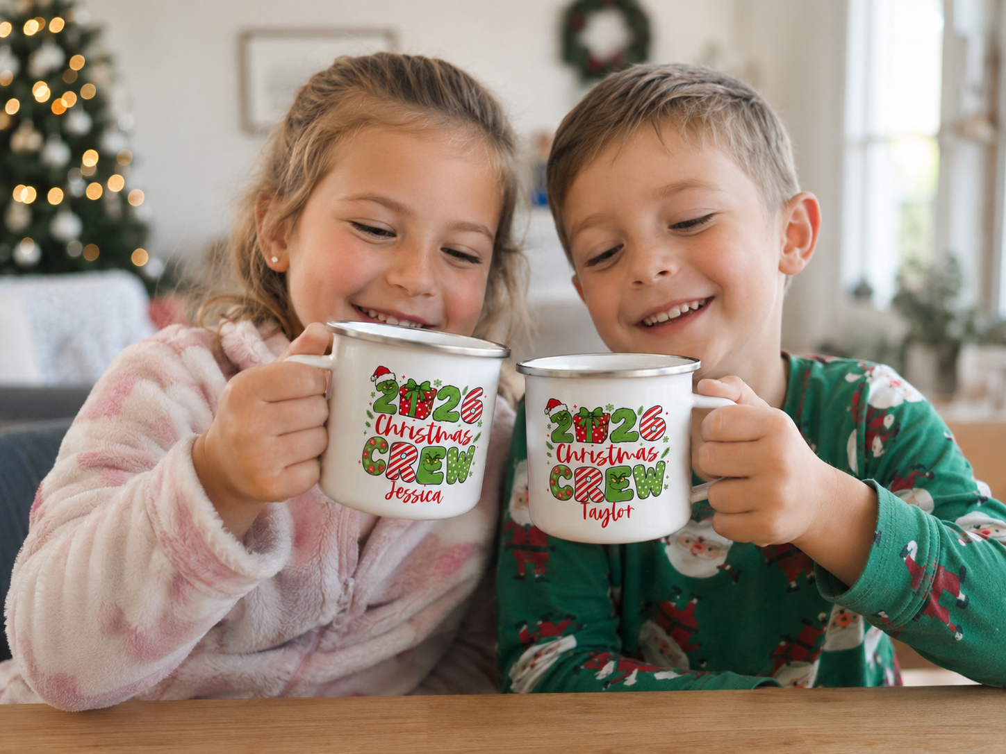 Two children holding 2026 Christmas Crew enamel mugs personalised with their own names