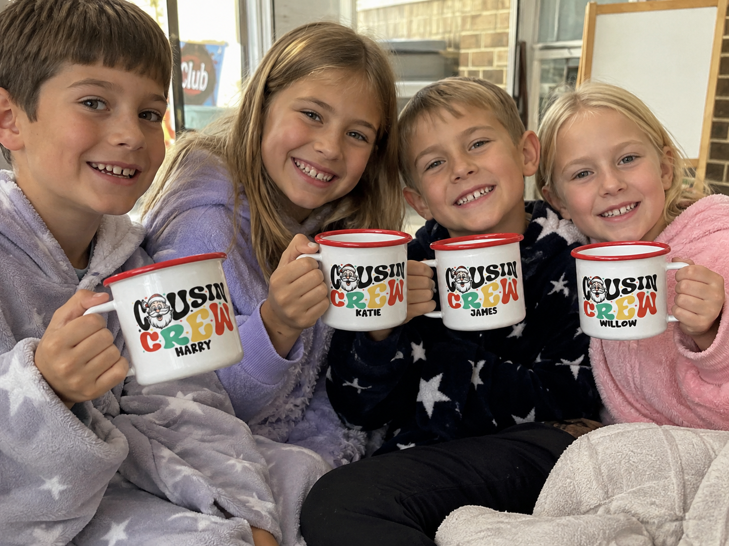 Four kids in pyjamas holding personalised Santa Cousin Crew enamel mugs together on the couch